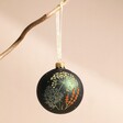 Green Floral Bauble Hanging on Branch Against Pink Surface