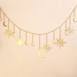 Gold Moon and Star Metal Garland hanging in front of beige coloured backdrop