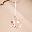Pink Floral Wreath Glass Bauble Hanging on Branch Against Pink Wall