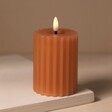 Pink Ribbed Wax LED Pillar Candle Lit on Beige Surface
