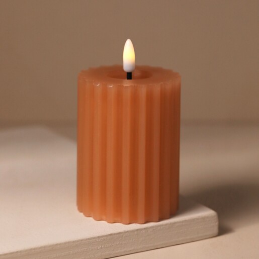 Pink Ribbed Wax LED Pillar Candle Lit on Beige Surface