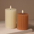 White and Pink Ribbed Wax LED Pillar Candles On Beige Surface