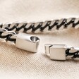 Close up of clasp on Men's Stainless Steel Black Cord Curb Chain Bracelet on top of beige coloured fabric