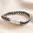 Men's Stainless Steel Black Cord Curb Chain Bracelet on top of a beige coloured fabric