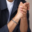 Men's Stainless Steel Black Cord Curb Chain Bracelet on model with hands clasped in front of neutral backdrop