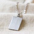 Close up of Pendant on Men's Stainless Steel Tag Pendant Necklace on Beige Fabric