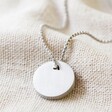 Men's Stainless Steel Disc Pendant Necklace on top of beige coloured fabric