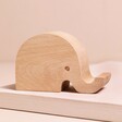 Wooden Elephant Phone Holder on top of raised beige surface