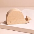Wooden Whale Phone Holder on top of raised beige surface