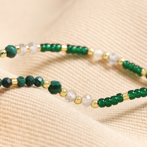 Close up of beads on Heart Chakra Beaded Necklace in Gold on beige fabric