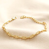 Anchor Chain Bracelet in Gold laid out on top of beige coloured material