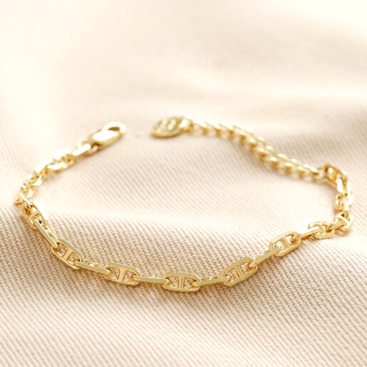 Anchor Chain Bracelet in Gold  Anchor Chain Bracelet in Gold laid out on top of beige coloured material