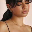 Model looking down wearing Anchor Chain Necklace in Gold with beige backdrop