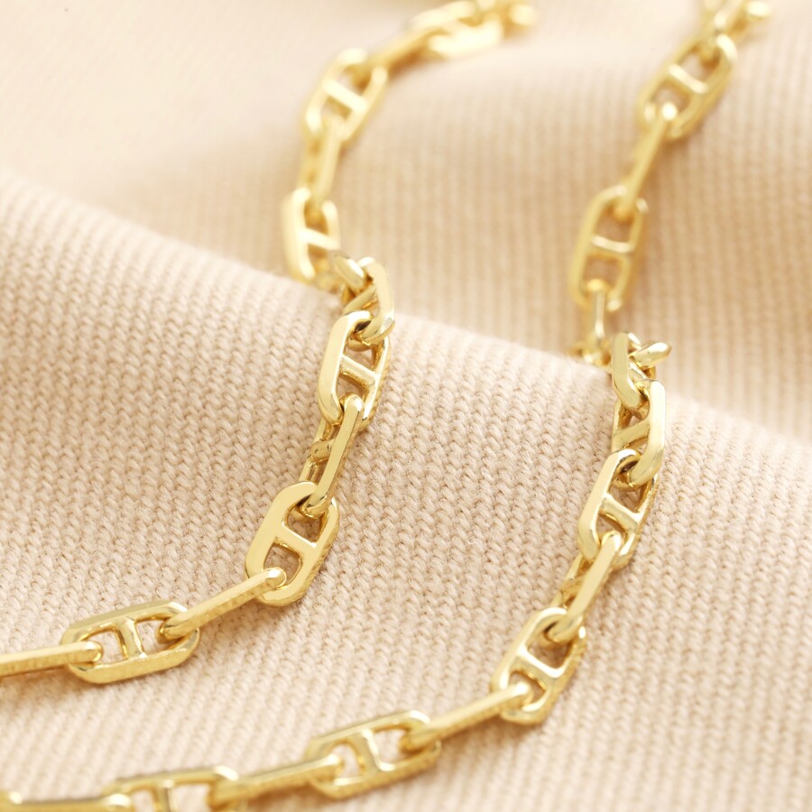 Anchor Chain Necklace in Gold arranged on beige coloured fabric