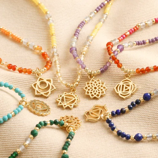 Root Chakra Beaded Necklace in Gold with other designs on beige coloured material