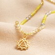 Solar Plexus Chakra Beaded Necklace in Gold on top of beige coloured surface