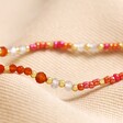 Close up of beads on Root Chakra Beaded Necklace in Gold on top of neutral coloured material
