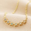 Close Up of Ombre Crystal Star Bar Necklace in Blue on Beige Fabric