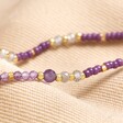 Close up of beads on Crown Chakra Beaded Necklace in Gold on top of beige coloured material