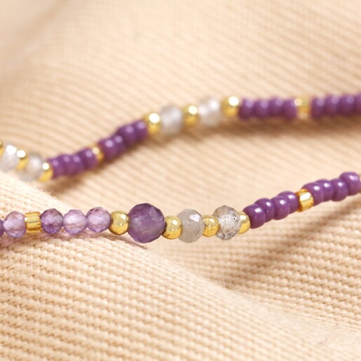Close up of beads on Crown Chakra Beaded Necklace in Gold on top of beige coloured material
