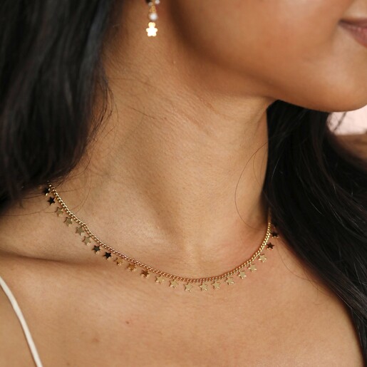 Close up of Tiny Star Charm Necklace in Gold on model