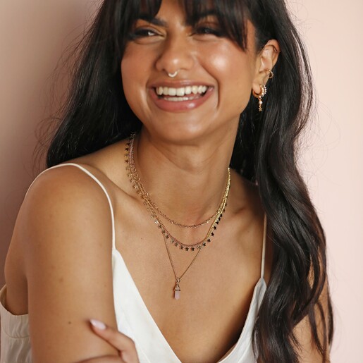Model laughing wearing Tiny Star Charm Necklace in Gold in front of neutral backdrop