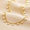 Tiny Star Charm Necklace in Gold on top of neutral coloured fabric