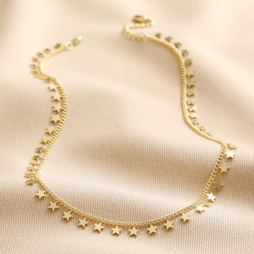 Tiny Star Charm Necklace in Gold laid out on top of neutral fabric