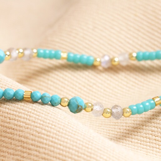 Close up of Throat Chakra Beaded Necklace in Gold on top of beige coloured fabric