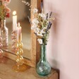 Lifestyle shot of Blue Glass Posy Vase on top of wooden counter with mirror and bubble candle holders in background