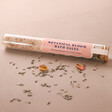 Botanical Bloom Himalayan Bath Salts Tube with Flower Petals Sprinkled in front on Beige Surface