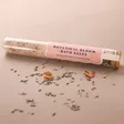 Botanical Bloom Himalayan Bath Salts Tube with Flower Petals Sprinkled in front on Beige Surface