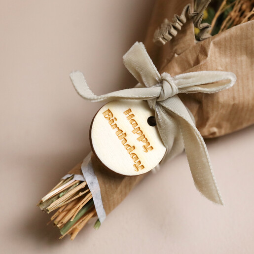 Close Up of Token on Posy in Happy Birthday Floral Wicker Gift Hamper on Plain Surface