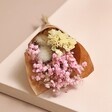 Dried flower posy from the Love You Candle and Mini Dried Flower Posy Gift lying on pink surface