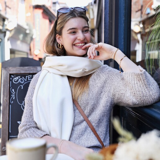 Model sitting at cafe wearing the Cream Cashmere Blend Scarf