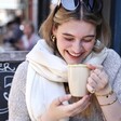 Model laughing with coffee cup while wearing the Cream Cashmere Blend Scarf