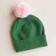 Green and Pink Pom Pom Bobble Hat on Beige Background
