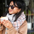 Model smiling wearing Personalised Initials Tan Tartan Winter Scarf holding coffee