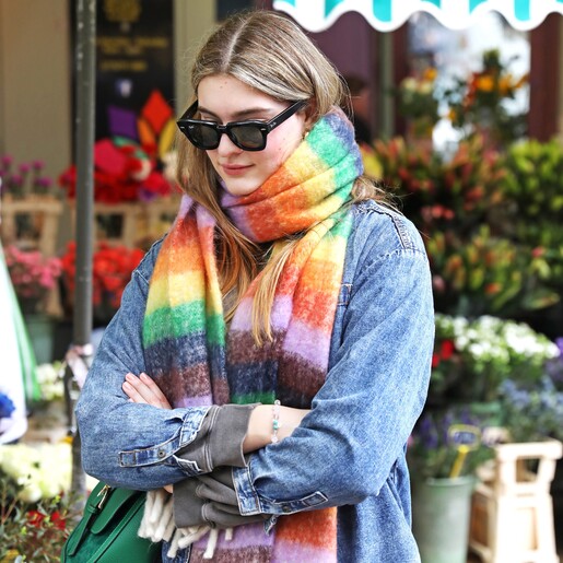 Model wearing Vibrant Rainbow Striped Winter Scarf with arms crossed and sunglasses on