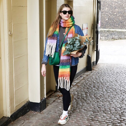 Vibrant Rainbow Striped Winter Scarf on model holding bunch of eucalyptus and wearing sunglasses
