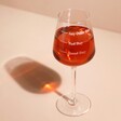 Personalised Measure Wine Glass full of rose in front of pink background