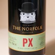 Close up of front of 500ml The English Distillery Norfolk PX Mixed Spirit Liqueur bottle against beige backdrop