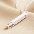 Personalised Bar Pendant Necklace in Silver with blackened engraving on top of beige coloured fabric