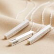 Personalised Bar Pendant Necklaces in Silver laid out on top of beige coloured fabric