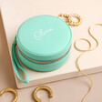 Personalised Mini Round Travel Jewellery Case in blue on neutral surface with jewellery out of case