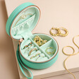 Personalised Mini Round Travel Jewellery Case in turquoise open on neutral coloured background
