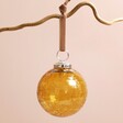 Amber Glass Bauble Hanging on Pink Background