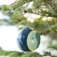 Hand-Painted Winter Moon Bauble in Christmas tree with lights behind 