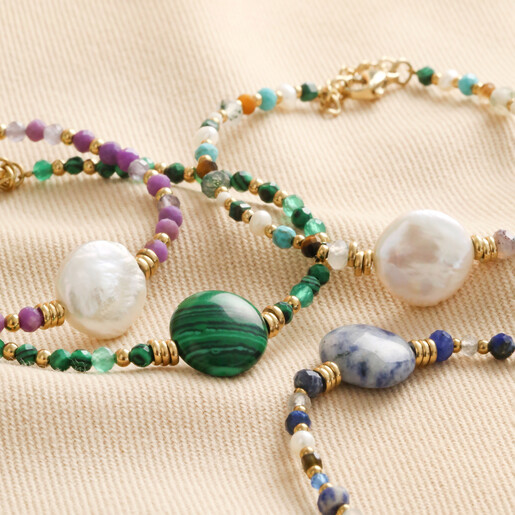 Purple Crystal and Pearl Beaded Bracelet with other designs on top of beige fabric