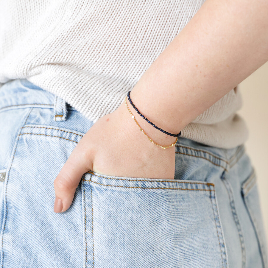 Model wearing Delicate Blue Stone Beaded Chain Layered Bracelet in gold with hand in pocket
